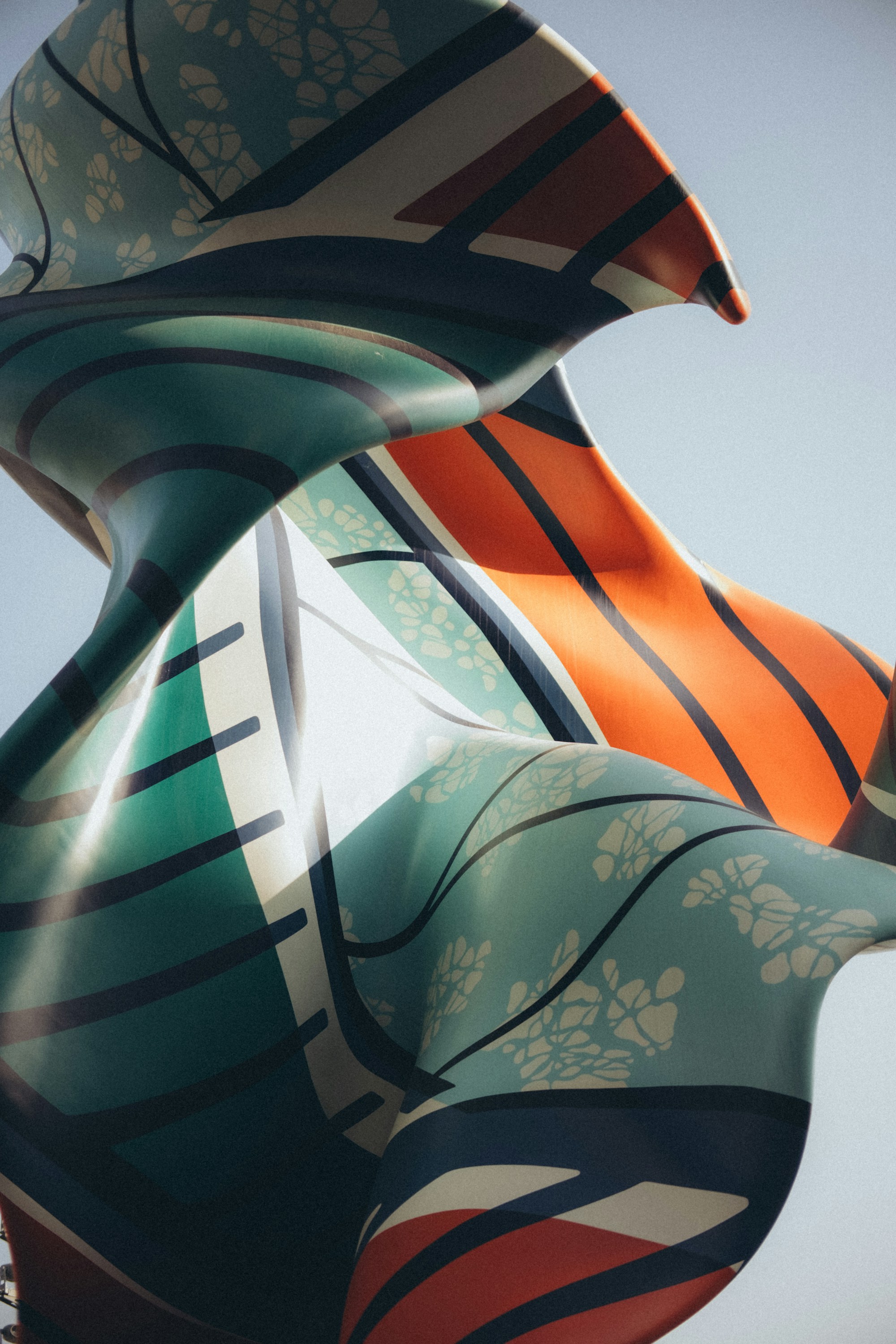 Flowing blue, teal, and orange patterns across an abstract sculpture