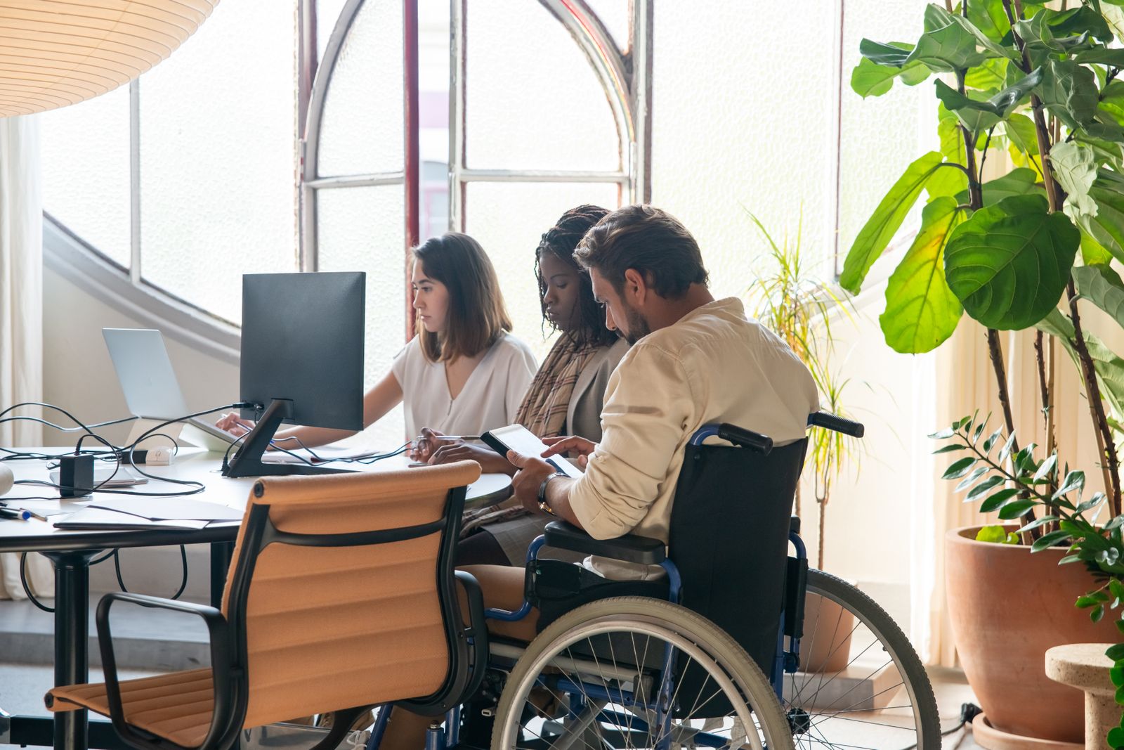 Three colleagues collaborating at a shared desk in a bright office